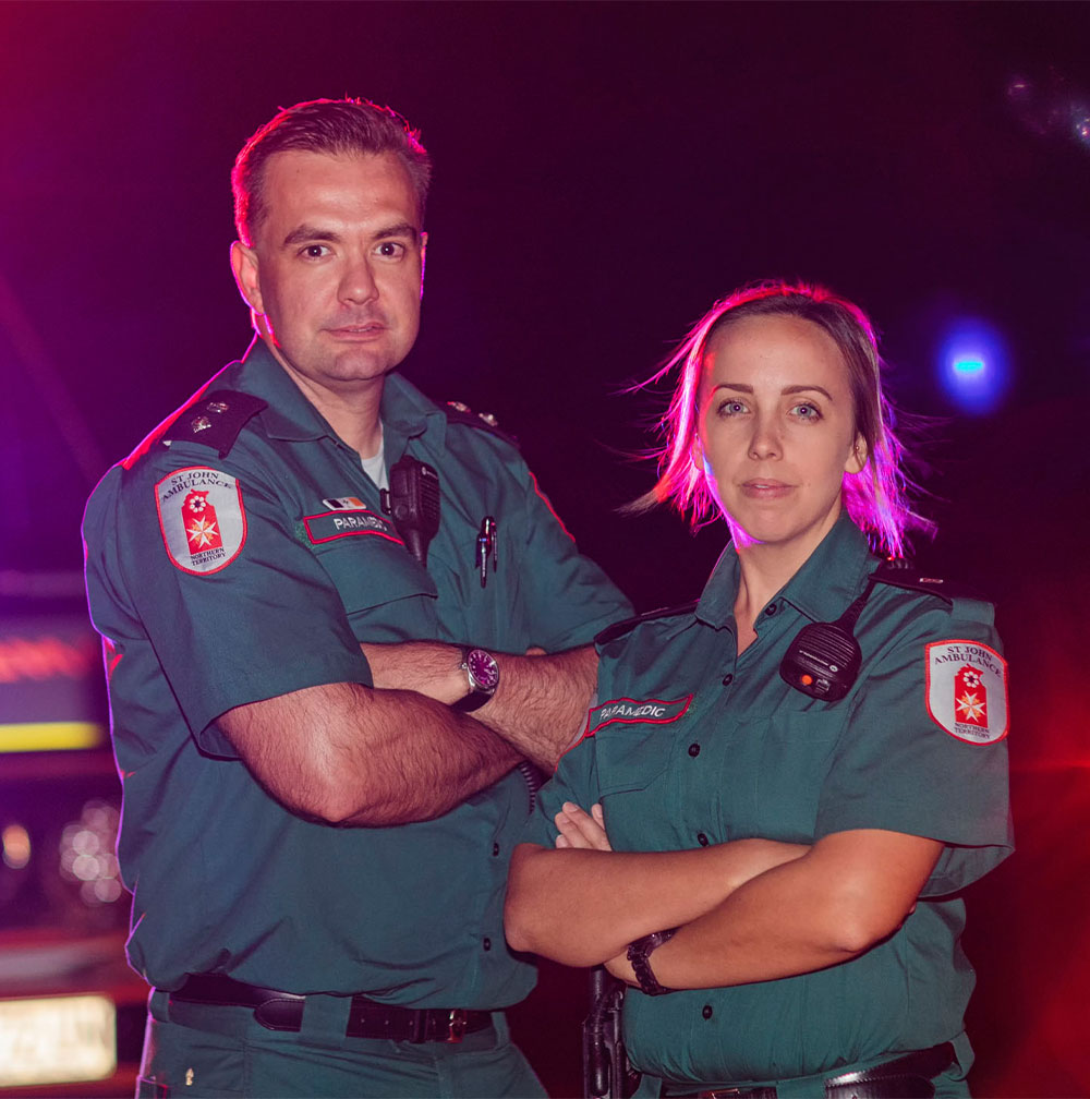 A male and female paramedic from St John ambulance NT pose in front of an ambulance